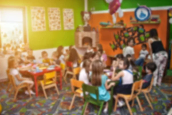 Arka plan kullanımı için doğum günü partisinde çocukların ve öğretmenlerinin bulanık görüntüsü.