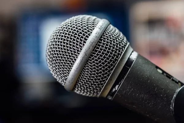 Old, scratched and used microphone on a stand in a studio. Blurred background, close up.