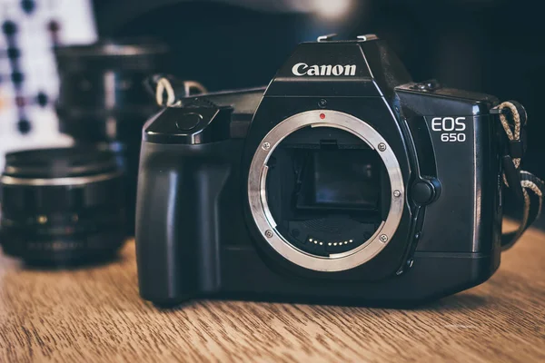 Ahşap masada eski bir Japon film kamerası. Model Canon EOS 650, otomatik odaklama sistemine sahip ilk SLR. Ön manzara, yakın çekim, canlı bir ton..