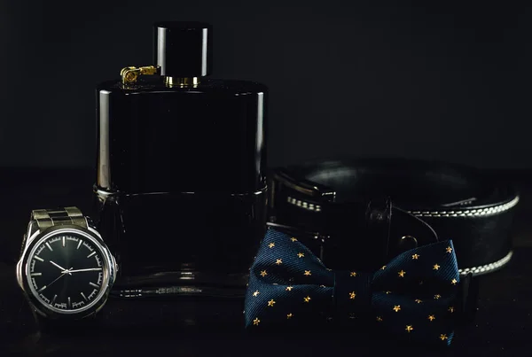 Bowtie Perfume Bottle Leather Belt Silver Wristwatch Dark Wooden Table — ストック写真