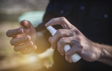 Close up of hands applying alcohol spray sanitizer outdoors. Antiseptic anti bacterial spray to prevent spread of germs, Covid-19 corona virus and bacteria. Pandemia outbreak, quarantine concept.