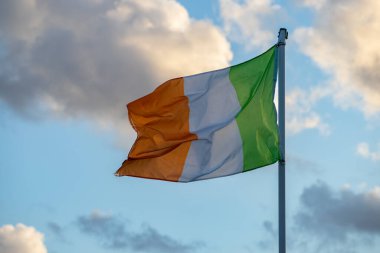 flag of the republic of ireland blowing in the wind with a beautiful sky in the background