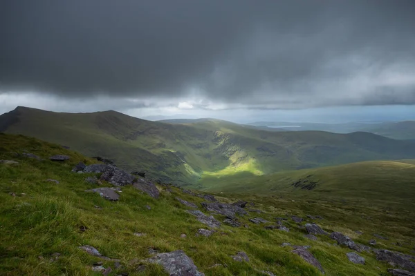 Spectacular view showing a landscape of Ireland with hills, green meadows and the sea, sunny and cloudy sky