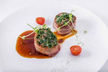 Domatesli kızarmış et parçaları taze bezelye filizleri, sos ve yuvarlak tabakta maydanoz. Yatay yönelim