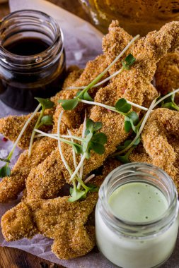 Mung fasulyesi salatalı kızarmış balık parçaları ve iki çeşit sos tabakta ve ahşap zemin üzerinde. Dikey yönelim