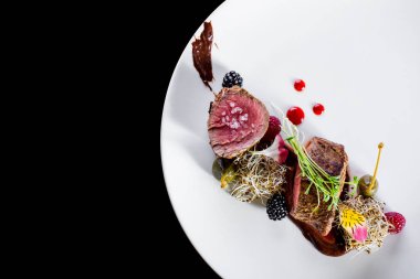 Pastırmalı kuzu kızartma, patates, dantelli cips, arka planda çiçek yaprakları. Dikey yönelim