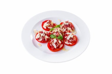 Taze domates dilimlenmiş, üzerinde ince doğranmış badem ve fesleğen yapraklı pastırma var. Aperatif beyaz bir tabakta. Beyaz arkaplan