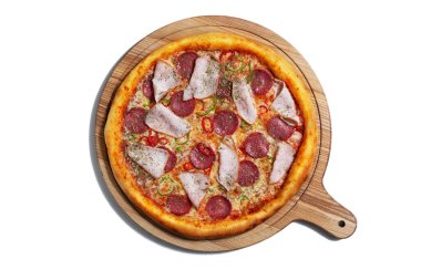 Pizza with cheese, ham, sausages, pepper onions and sauce on a wooden board on a white plate