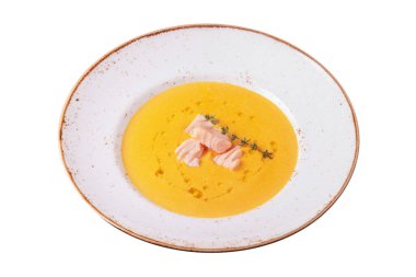 Pumpkin sauce with thyme and fish pieces in a plate on a white plate