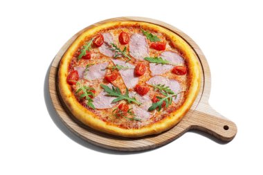 Pizza with cheese, arugula, tomatoes, ham and sauce on a wooden board on a white plate