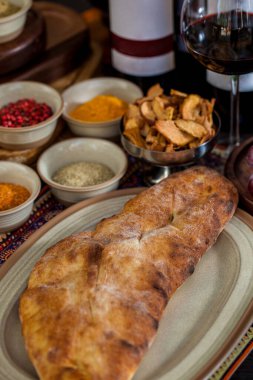Oval tabakta Kubdari, üzümler, kurutulmuş elmalar, baharatlar, bir bardak kırmızı şarap. Dikey yönelim 