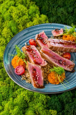 Domatesli kızarmış ton balığı, pilav, bezelye ve yeşil arka planda yuvarlak tabakta taze filizler. Dikey yönelim