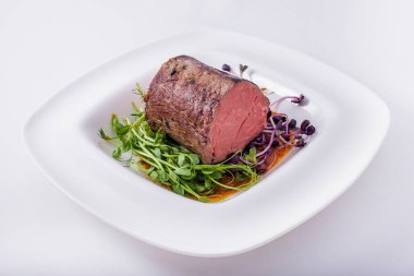 Yeşil soğanlı kızarmış et parçaları, maydanoz, biber ve taze bezelye filizleri tabakta ve beyaz tabakta. Yatay yönelim