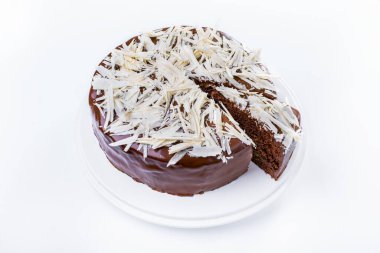 Beyaz tabak ve beyaz tabakta rendelenmiş beyaz çikolata parçalarıyla çikolatalı pasta. Yatay yönelim