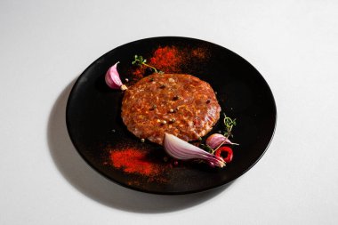 Fried beef meat with peppercorns, onions, paprika, salt, thyme and garlic in a plate on a white background