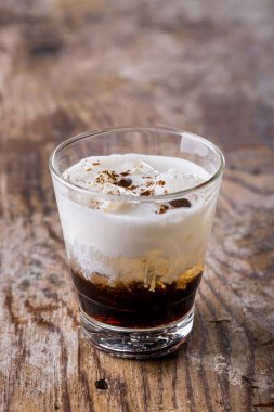 Cocktail with chocolate, ice, ice cream and nuts in a glass on a wooden table
