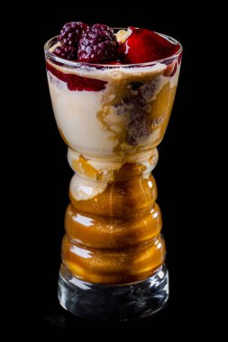 Viski, dondurma, böğürtlen şurubu ve böğürtlenli İrlanda kahvesi. Bir bardak bardakla iç. Cam kumaştan yapılmış siyah bir arkaplanda duruyor..