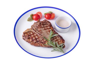 Grilled meat steak on the bone with rosemary, sauce in a bowl, basil, tomatoes in a plate on a white plate