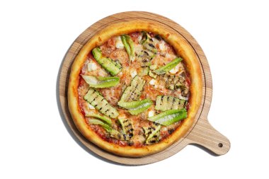 Pizza with cheese, salad, zucchini and sauce on a wooden board on a white plate