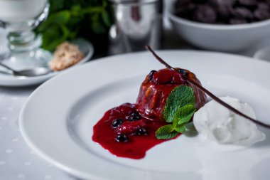 Çikolata parçalı tatlı, yaban mersini, ahududu, karamel, nane şekeri, bir top dondurma ve beyaz tabakta bir fincan kahve. Yatay yönelim