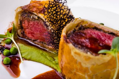 Ekmek kabuklu kızarmış et, bezelye sosu, yeşil bezelye, beyaz tabakta sığır eti salatası ve bir bardak şarap. Yatay yönelim