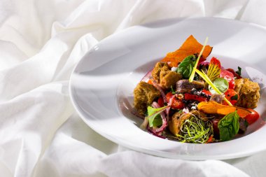 Caesar salad with onions, bread, young shoots, basil, and cheese in a plate on a light background
