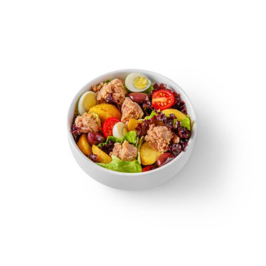 Salad with fish, egg, grapes, potatoes, lettuce and tomatoes in a plate on a white background