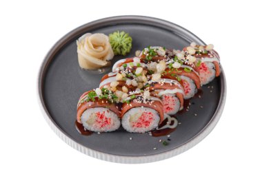 Roll with salmon, sesame seeds, sauce, crab, cucumber, rice, nori, onion, wasabi and ginger in a dish on a white plate