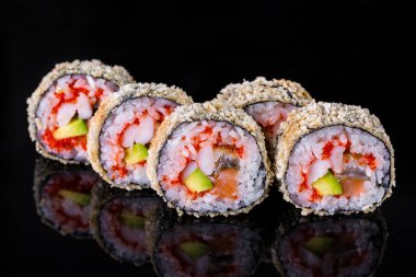 Roll with eel, shrimp, salmon, rice, nori, avocado, tobiko caviar and batter on a black mirror background