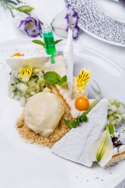 Çiçek yapraklı tatlı, beyaz cips, dondurma kepçesi, nane, krema ve hafif arkaplanlı bitki salatası. Dikey yönelim