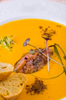 Somon etli çorba, masada ekmek olan bir tabakta taze filizler.