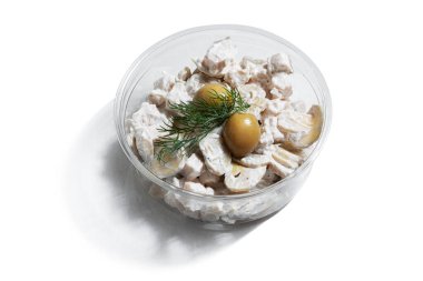 Mushrooms in a sauce with olives and dill in a plastic container on a white plate