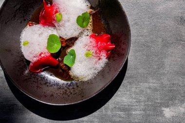 Red candy with apples, edible leaves, jam and froth on a plate and gray background