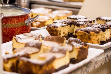 Kuru üzüm ve pudra şekerli kremalı güveç. Fırın için teneke bir tabağın üzerinde duruyor, aynı tencere ve güveç tepsilerinin arasında..