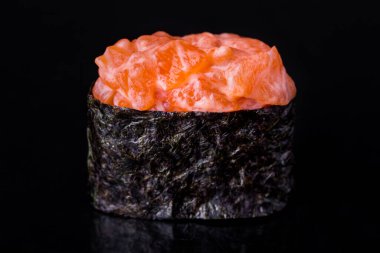 Roll with salmon, rice, nori and Philadelphia cheese on a black mirror background