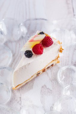 Şeffaf arkaplanda beyaz çikolata, böğürtlen ve ahududu olan bir parça peynirli güveç. Dikey yönelim
