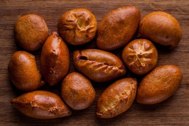 Tahta bir masada tavuklu bir sürü turta. Yatay yönelim 