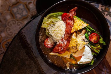 Salad with fried meat, fried chicken cutlet, boiled egg, tomatoes, parmesan, salad and sauce in a plate on the table