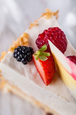 Şeffaf arkaplanda beyaz çikolata, böğürtlen ve ahududu olan bir parça peynirli güveç. Dikey yönelim