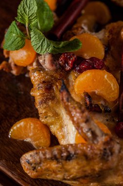 Tarçınlı ızgara tapaka tavuğu, baedyan, mandalina parçaları ve tahta bir tahtanın üzerinde nane. Dikey yönelim