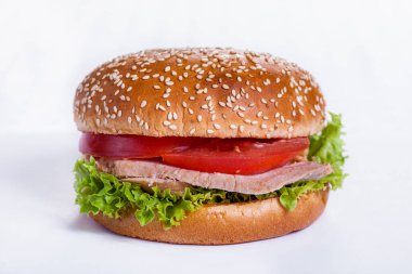 Burger with sesame bun, tomatoes, lettuce, ham and cheese on a white background. Horizontal orientation