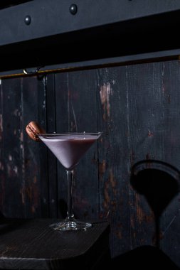 Milkshake with macaroni in a glass that stands on the table against the background of a dark green wall