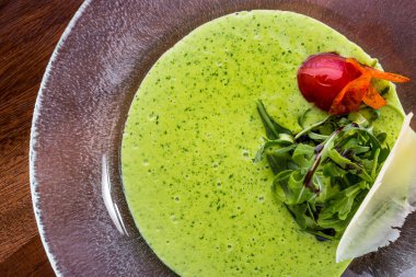 Salatalı yeşil çorba, roka, domates ve bitkiler bir tabakta