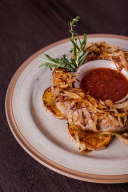 Izgara domuz sosisi, kızarmış soğanlı ve acılı patates dilimli. Ahşap arkaplan.