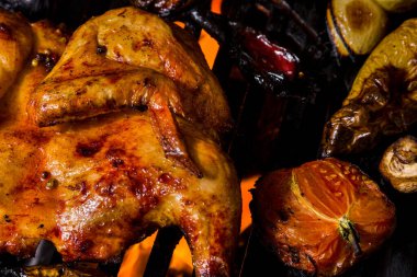 Paprikayla marine edilmiş tavuk tabakası sebzelerle kızartılır. Izgaranın altından ateş görülebilir. Yakınlarda yarım domates, yeşil soğan, patlıcan, kırmızı biber var..