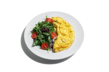 Omelet with arugula tomatoes and basil in a plate on a white plate