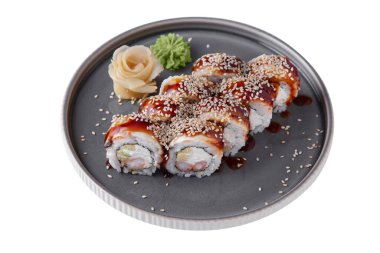 Rolls with eel, sesame seeds, sauce, shrimps, cucumbers, rice, philadelia cheese, nori, wasabi and ginger in a dish on a white plate