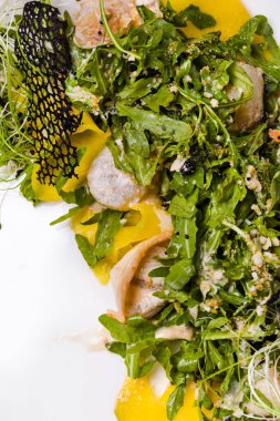 Kalamarlı salata, taze filizler, roka, hindiba, biber, dantel cips, salata ve susam tohumlu hafif bir arka planda.