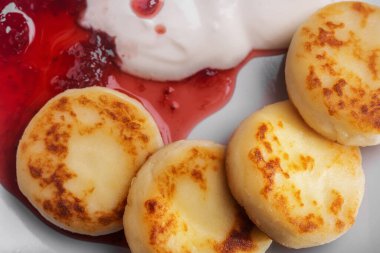 Pancakes in a plate with sour cream and jam on a plate