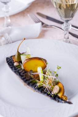 Kızarmış uskumru, patates, salatalık ve kocchini hafif arka planda beyaz yuvarlak bir tabakta. Dikey yönelim